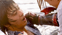 two wet men clutch at each other in shallow water